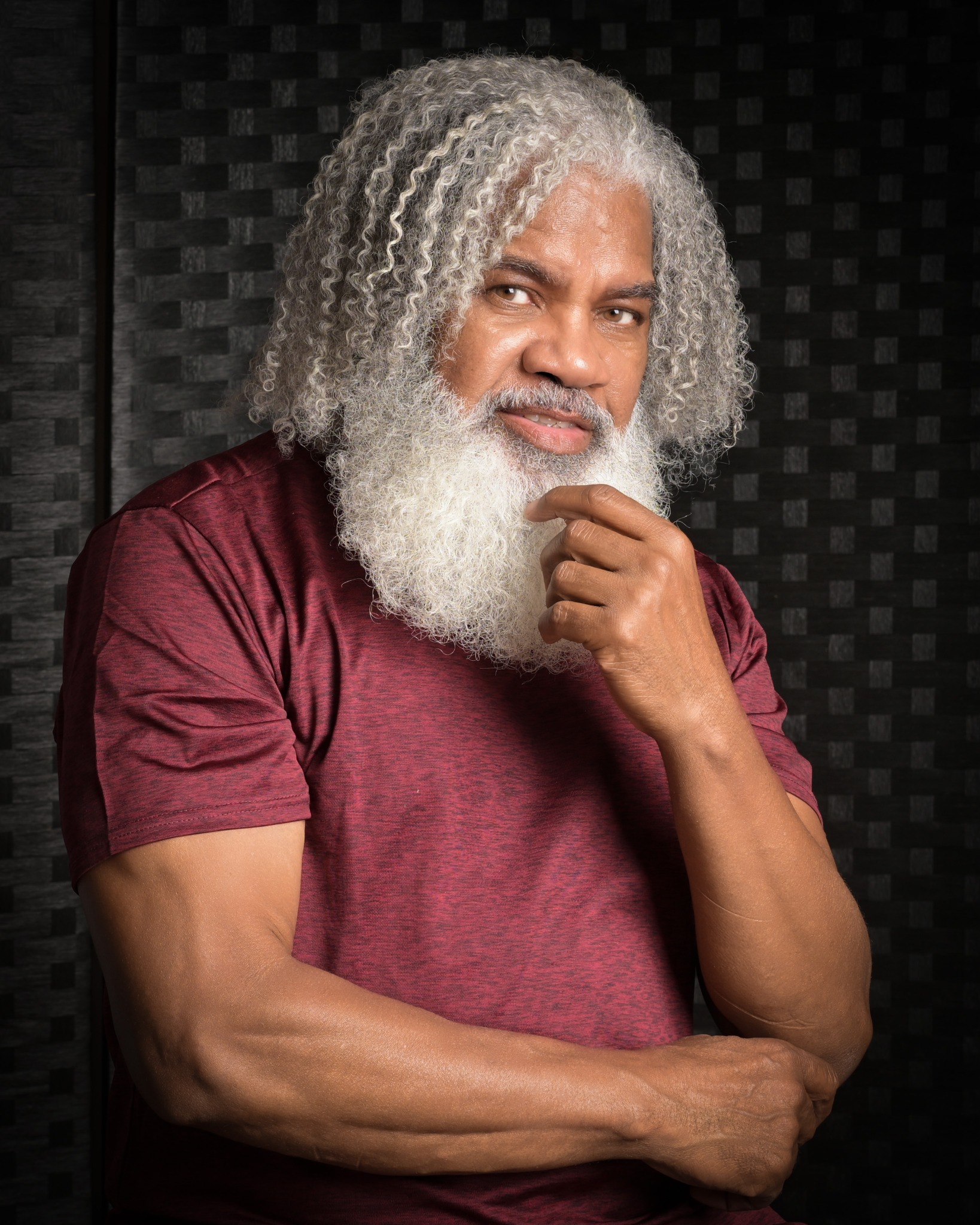 Leon McPherson, photographer and founder of Alpha Leon Creative Studio, in a burgundy shirt against a dark backdrop